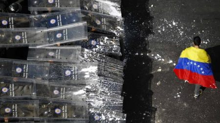 Un manifestante venezolano camina tranquilamente frente a policías anti disturbios del Gobierno. Foto: Tomada de BBC Mundo